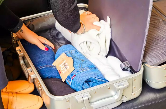 Individual organizing clothes into the Away The Bigger Carry-on: Aluminum Edition