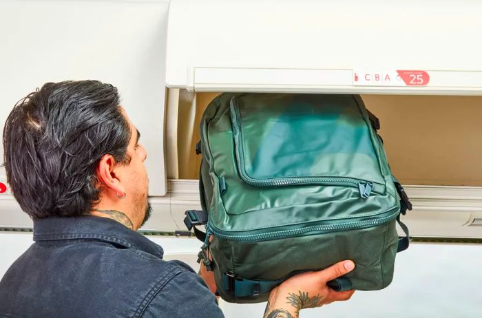 A person stows the Away F.A.R. Convertible Backpack 45L in an overhead compartment.