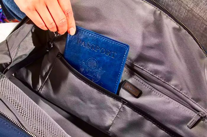 A person places a passport into the Away Everywhere Bag.