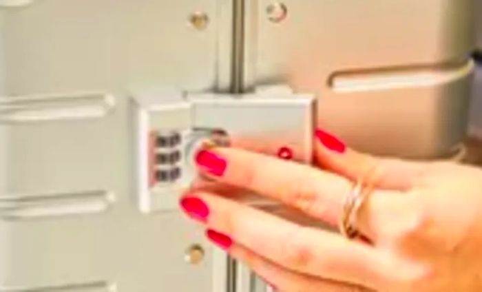 Close-up view of a hand on the combination lock of the Away The Bigger Carry-on: Aluminum Edition