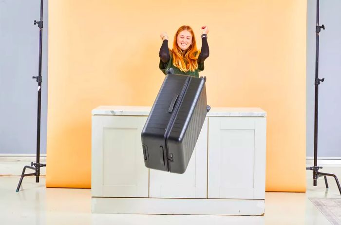 A person sliding the Away The Trunk off a counter