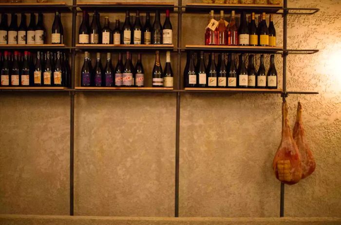 Close-up of a wall adorned with wine bottles and cured meats at Ester in Sydney, Australia