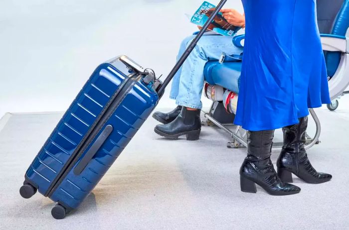 Individual maneuvering Away The Bigger Carry-On past airplane seats.