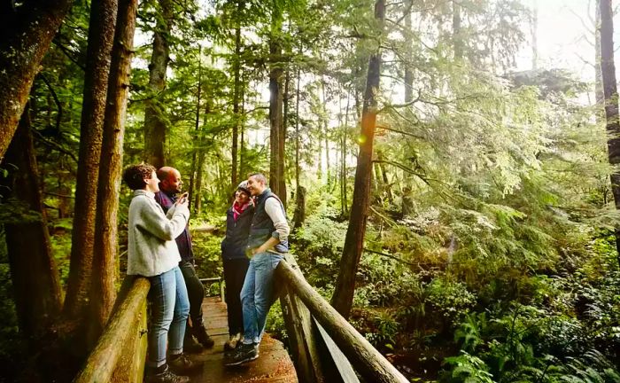 A group of individuals stands on a wooden bridge surrounded by trees.