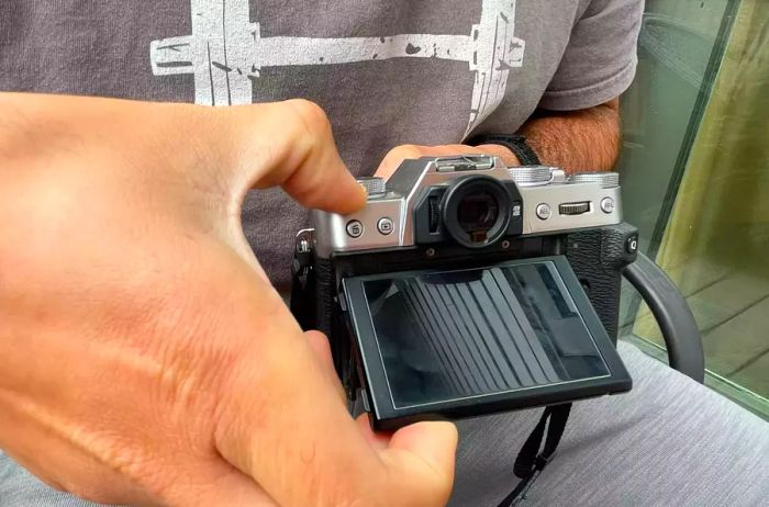 An individual activating a button on the Fujifilm X-T30 II while adjusting the screen