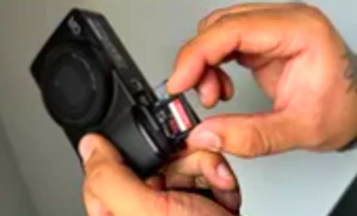 individual inserting a memory card into the Ricoh GR III Digital Camera