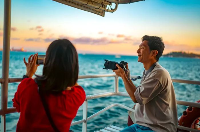 A couple captures memories with a camera and a phone while on a tour boat.