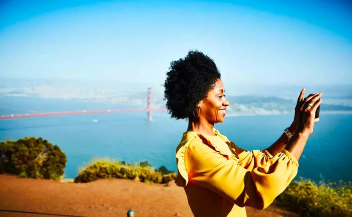 A woman snapping pictures by the Golden Gate Bridge in San Francisco