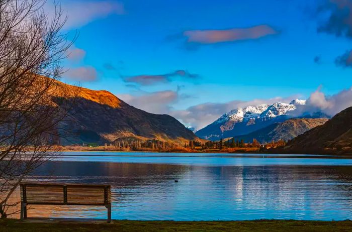 A scenic bench overlooking a serene lake and majestic mountains in New Zealand