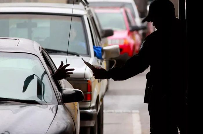 A Customs and Border Protection officer verifies IDs from drivers entering the United States from Mexico.