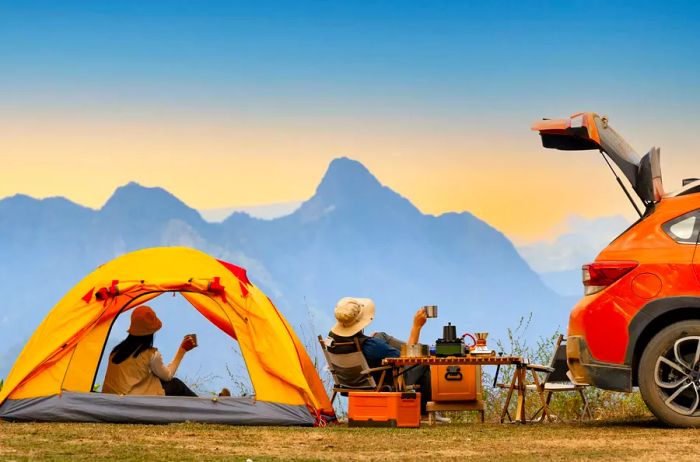 Couple camping in the mountains next to their car on a road trip