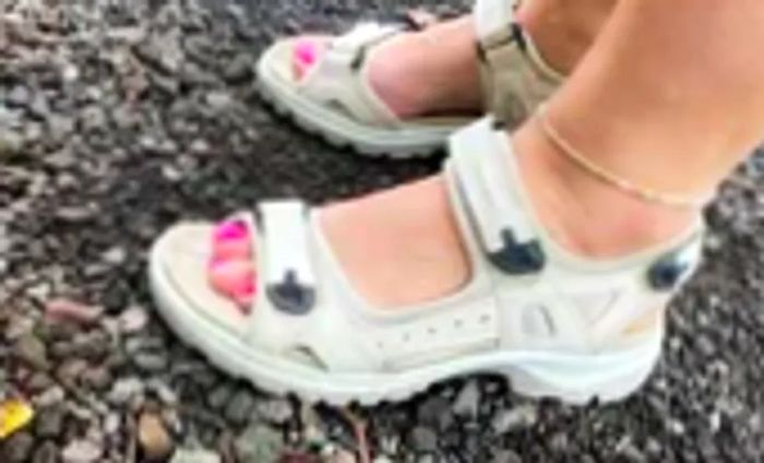 A woman is seen wearing the ECCO Yucatan Sport Sandal while traversing rocky terrain