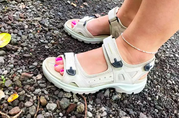 A woman is seen wearing the ECCO Yucatan Sport Sandal while navigating rocky terrain