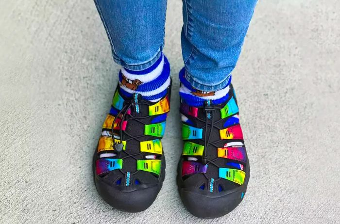 A person is seen standing on concrete wearing KEEN Newport H2 Closed Toe Water Sandals