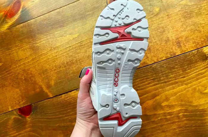 A woman lifts the ECCO Yucatan Sport Sandal to showcase the sole of the shoe