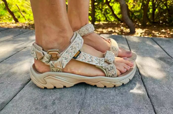 A person stands on wood while wearing Teva Terra Fi 5 Universal Sandals