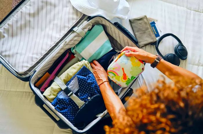 A woman at home, packing her suitcase for a getaway.