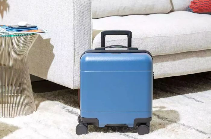 Calpak Hue Mini Carry-On Luggage showcased on a rug beside a sofa