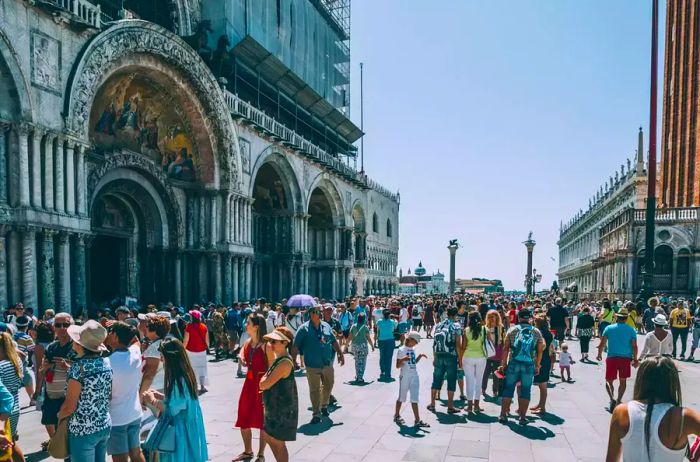 Tourists gather outside St. Mark's Cathedral in Venice, Italy during the summer season