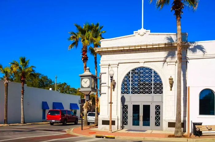 Image capturing a street scene featuring a small office building and a street clock in downtown Panama City, Florida, USA, under a clear blue sky.