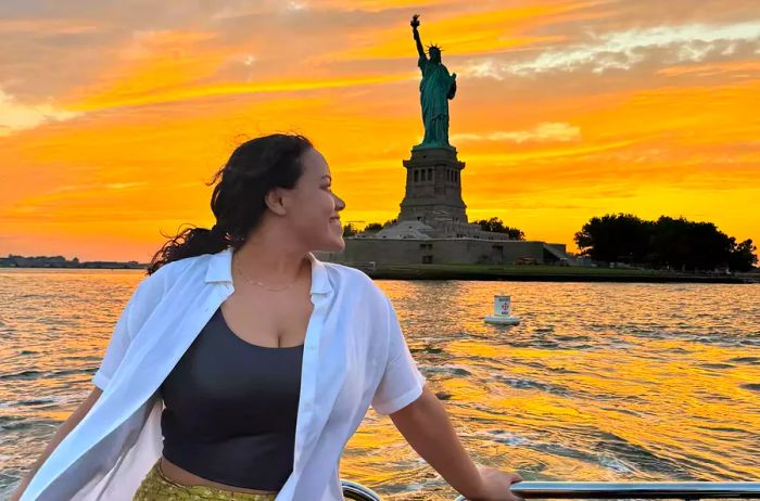 A woman aboard the Aman New York Yacht as it sails past the iconic Statue of Liberty.