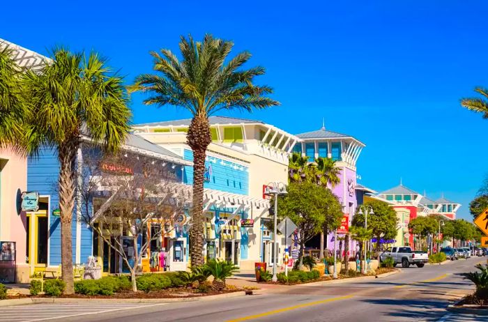 An image of a vibrant street lined with colorful storefronts in downtown Panama City Beach, Florida, under a clear blue sky.