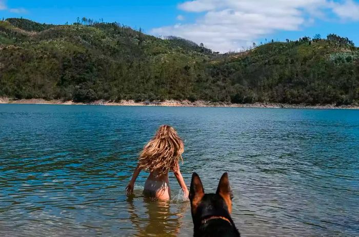 A woman enjoying the river with her dog at Praia Fluvial Alqueidão, Portugal.