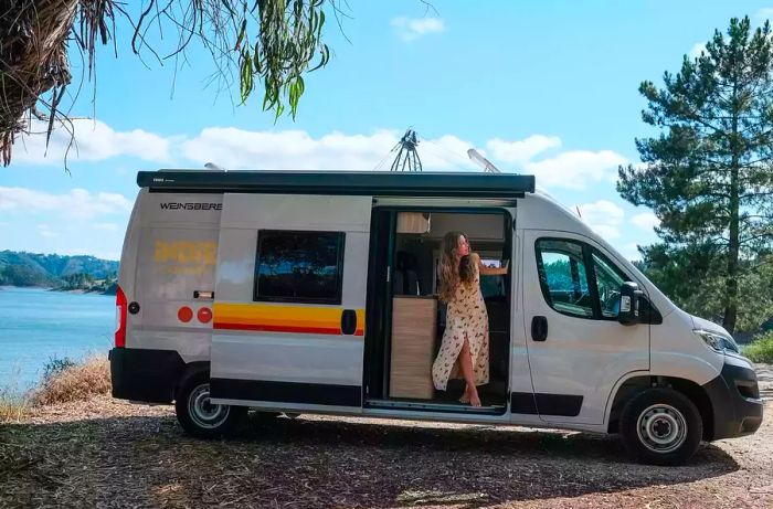 A camper van parked by a river at Praia Fluvial Alqueidão, Portugal.