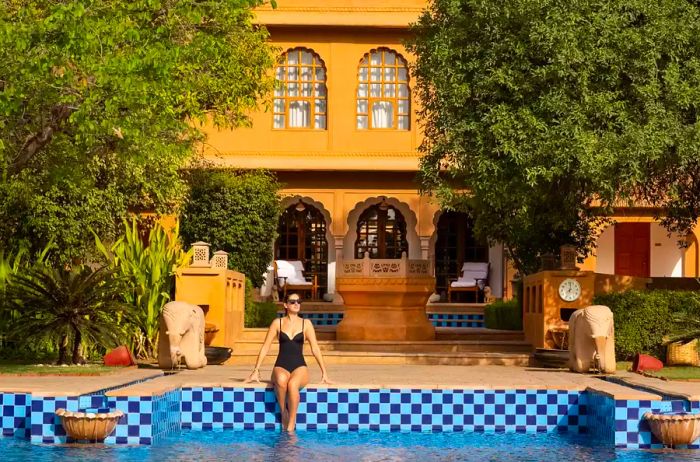 A woman relaxes by the pool at the Oberoi Rajvilas hotel