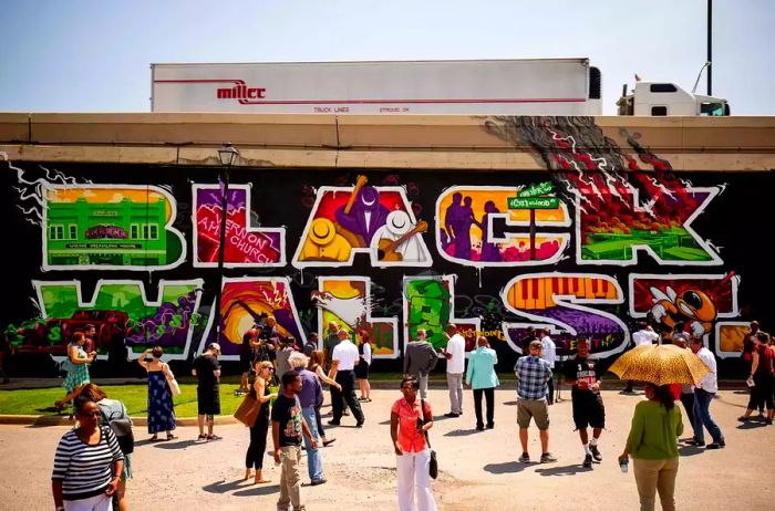 Visitors pose in front of the Black Wall Street Mural located in Tulsa, Oklahoma