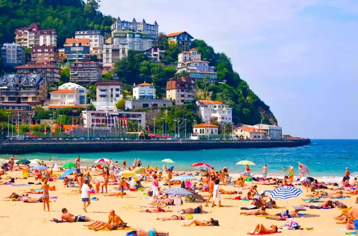 Beachgoers enjoying the sun on Ondarreta beach in San Sebastian, Spain