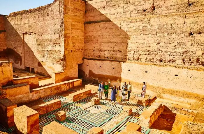 A sweeping view captures a group of tourists exploring the ruins of El Badi Palace alongside a tour guide during their vacation in Marrakech.