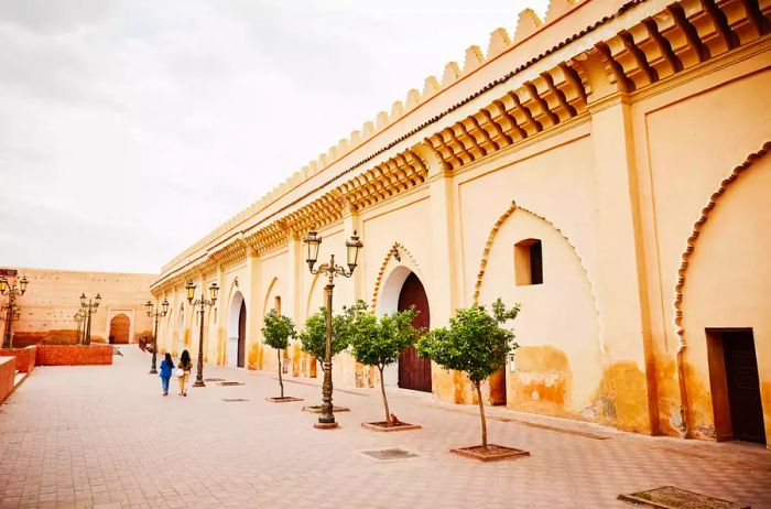 An expansive view captures female friends enjoying an early morning walking tour through the Medina of Marrakech during their vacation.