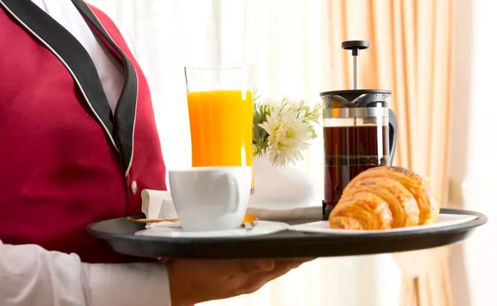 Hotel staff delivering a tray of room service breakfast