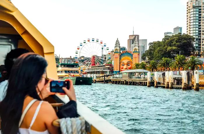 A person capturing a photo of the Sydney skyline from a ferry