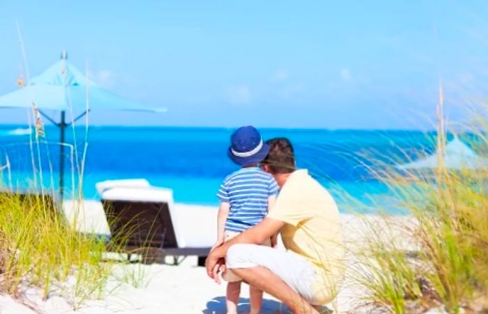 A father and son gazing at the stunning crystal blue waters of Fortune Beach in Freeport, Bahamas.