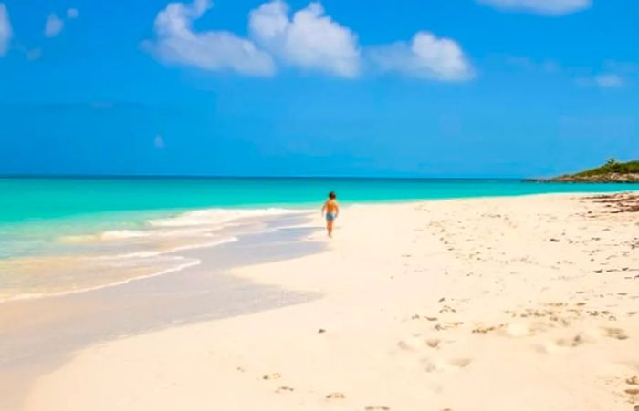 A young boy joyfully running along the shoreline of Smith’s Point Beach in Freeport, Bahamas.