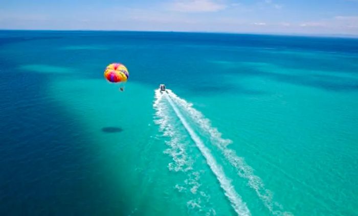 An aerial shot of a couple enjoying parasailing over the expansive Mexican waters