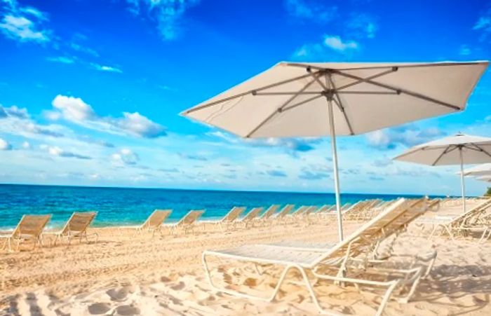 A white umbrella and beach chairs set against the stunning sands of Lucaya Beach in Freeport, Bahamas.