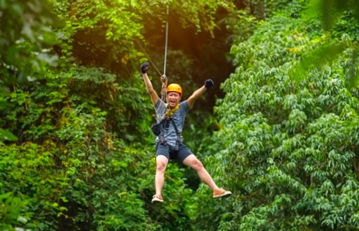 A man triumphantly raising his arms while zip lining in Mazatlan, Mexico