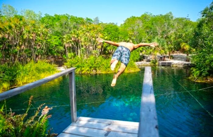 A person diving from a wooden platform into a cenote in Mexico