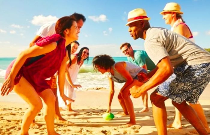 family enjoying a game of football on the beach in the Caribbean