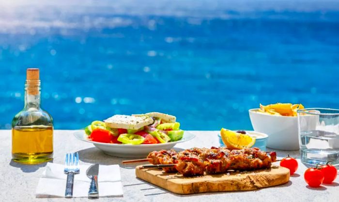 Enjoying souvlaki and Greek salad with the dazzling blue Aegean Sea as a backdrop.