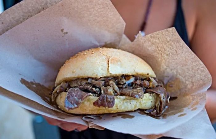 A woman enjoying pani ca meusa, a beloved lamb sandwich in Palermo