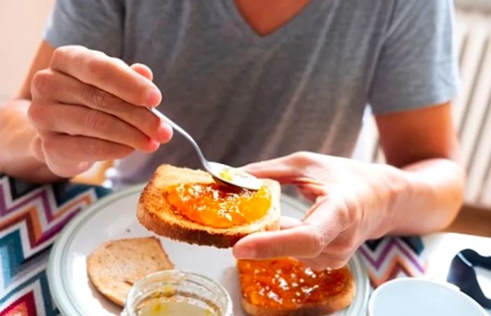 a person applying orange marmalade