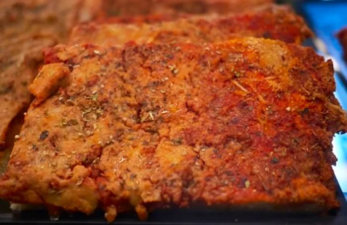 A slice of Sicilian sfincione pizza displayed in a shop in Palermo