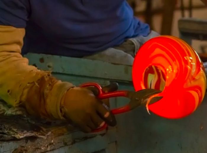 a glassblower completing their glass sculpture