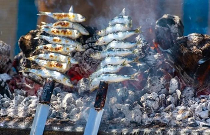 sardines, or espetos, grilling over a barbecue in Málaga, Spain