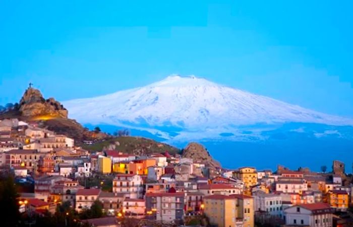 a sweeping view of Mount Etna overlooking a village