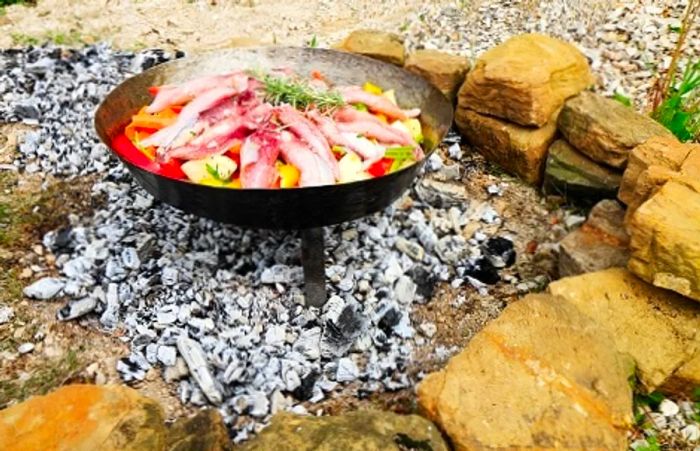 a metal oven, known as a sač, cooking food over hot coals